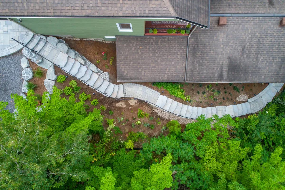 Overhead view of a curved paved path beside a house