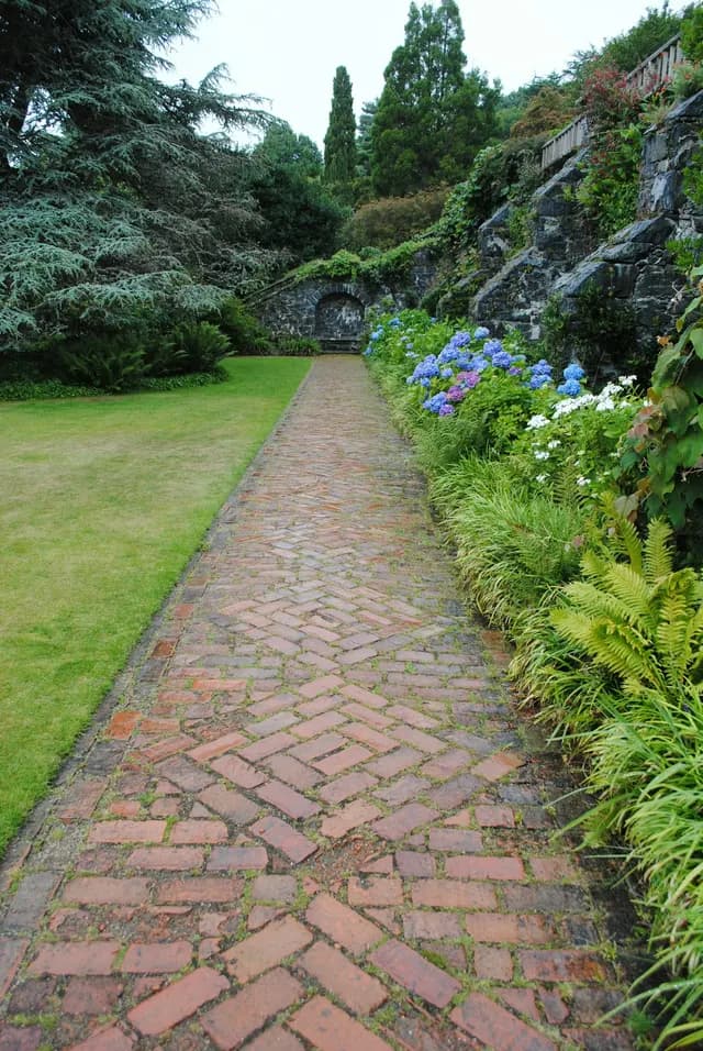 Brick garden path leading between planted beds