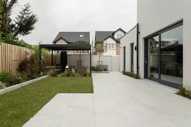 Long paved garden terrace beside a lawn and shade structure